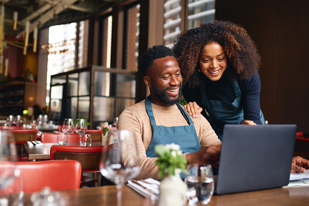 A couple in a restaurant with a laptop